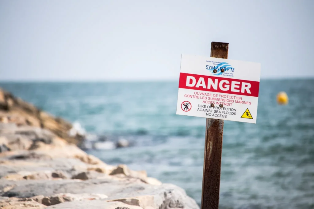 Beach safety warning sign about ocean hazards and restricted areas